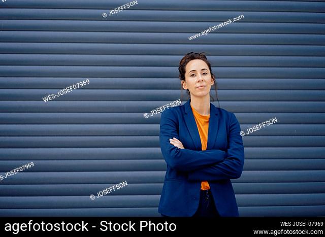 Businesswoman with arms crossed standing in front of closed shutter
