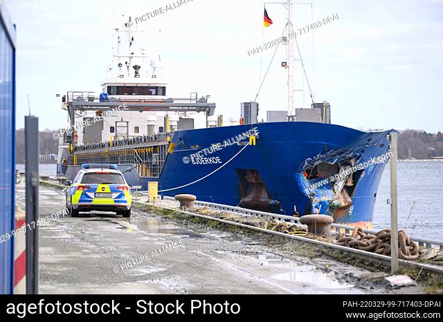 29 March 2022, Schleswig-Holstein, Kiel: A patrol car stands next to the heavily bow-damaged ""Bjoerkoe"" on the quay of a building materials store