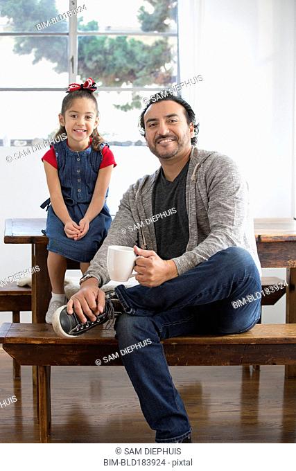 Hispanic father and daughter smiling at table