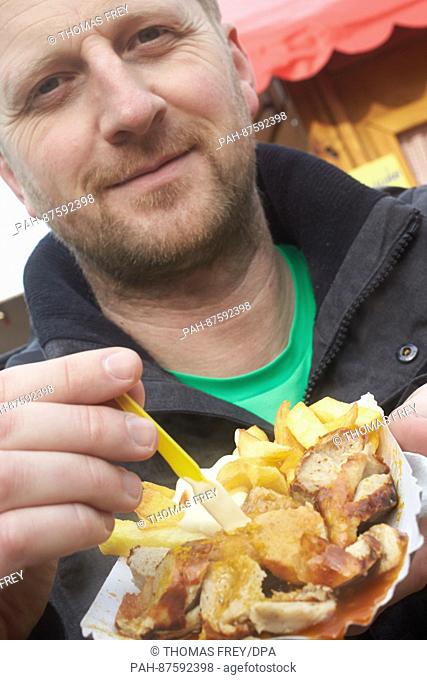 Michael is eating a curry sausage with french fries at the festival of the curry sausage in Neuwied, Germany, 27 January 2017