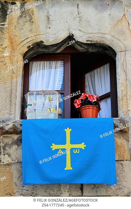 Window with Asturias flag and canary in a cage and flowers, in Llanes, Asturias, Spain