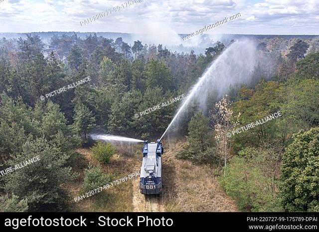 27 July 2022, Brandenburg, Falkenberg: A water cannon of the Brandenburg police extinguishes a forest fire. Firefighters in Brandenburg continue to fight a...