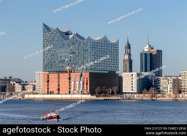 25 December 2020, Hamburg: The building of the Elbphilharmonie (l-r), the tower of the main church St. Michaelis and the Kehrwiederspitze shine in the winter...