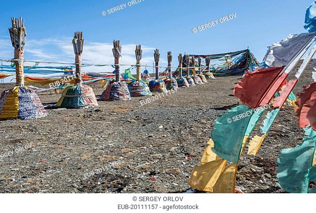 Buddhist sacred religious place at the Tibetan mountain pass with a lot of waving colorful prayer flags