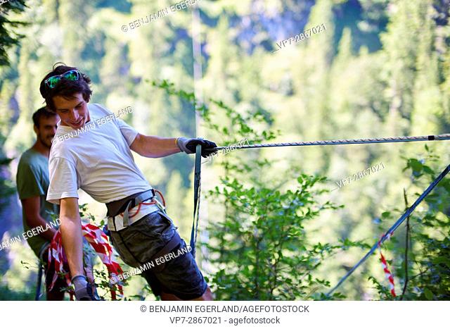 young outdoor sportsmen preparing rope for slackline in south of Germany, Bavaria, near border to Austria