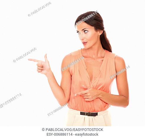 Fashionable lady pointing to her right and looking to her right in white background - copyspace