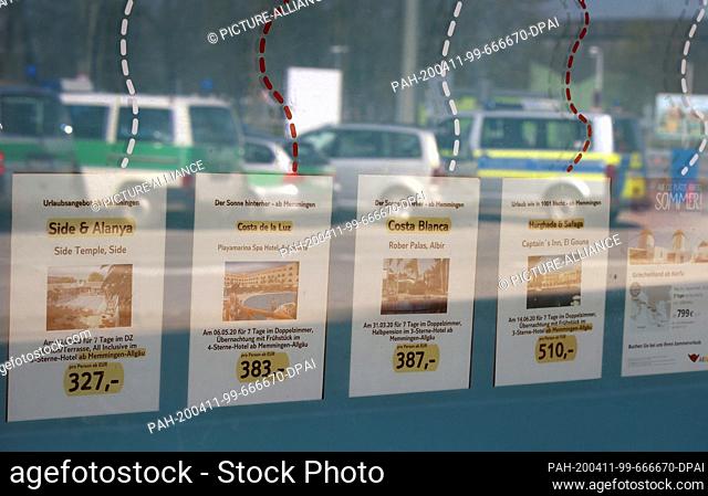 08 April 2020, Bavaria, Memmingen: In a window in which police cars are mirrored, advertising for air travel is carried out at the closed Allgäu-Airport