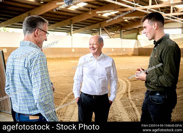 14 September 2023, Bremen: Chancellor Olaf Scholz (M, SPD) visits an indoor riding arena on the organic farm together with farmer Max Sündermann (r) and parents...