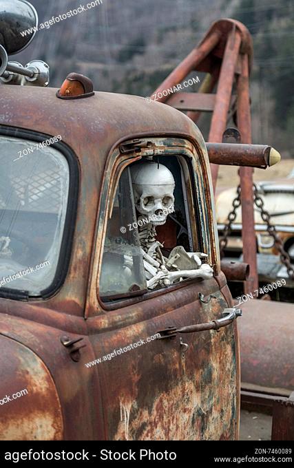 Der Tod fährt mit Skelett am Steuer eines alten Schrottautos