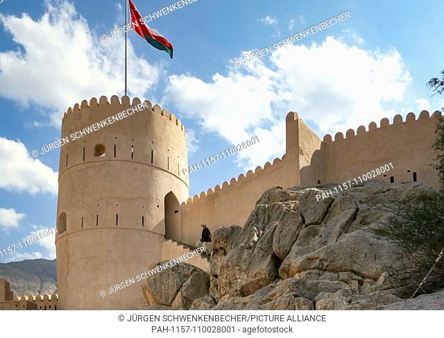 The Omani national flag flutters in the wind over a defensive tower of the fortress of Nakhl (Nakhal). | usage worldwide. - Nakhl/Oman