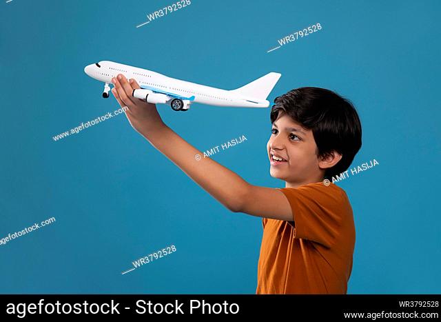 Boy playing with toy helicopter against blue background