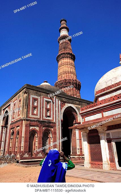Woman watching Alai Darwaza Imam Zamin's tomb and Qutab Minar built in 1311 red sandstone tower , Indo-Muslim art , Delhi sultanate , Delhi