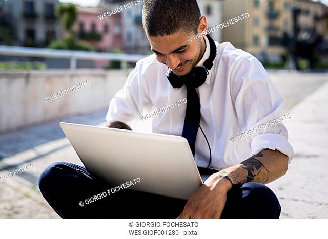 Smiling young businessman looking at laptop