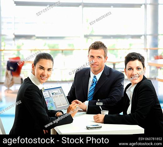 Young businesspeople having a business meeting at coffee table in office lobby, using laptop computer