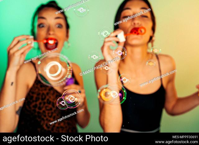 Two friends blowing soap bubbles