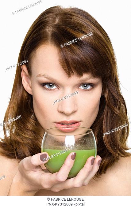 Young woman holding glass of wheatgrass juice