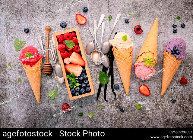 Various of ice cream flavor in cones with berries in wooden box setup on concrete background. Summer and Sweet menu concept