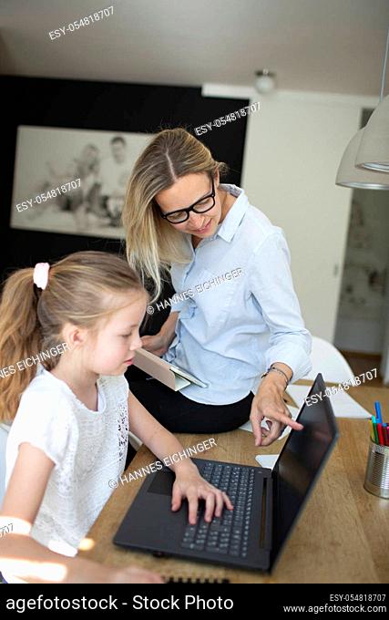 pretty young woman works from home doing homeoffice and her daughter has homeschooling during corona crisis
