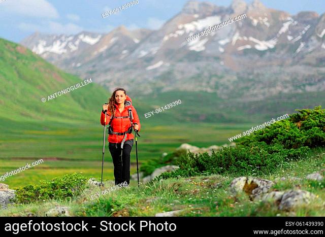 Front view portrait of a hiker walking in a green high mountain