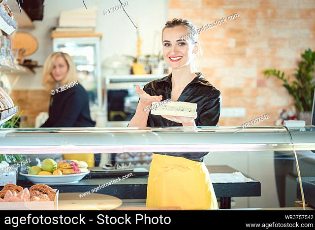 Friendly women selling cheese at counter in a supermarket