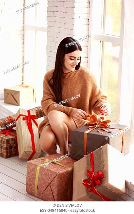 Beautiful girl in sweater sitting on the window. Gifts, new year