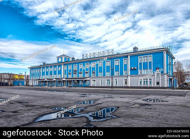 Murmansk, Russia - April 21, 2019: The main blue building of the Murmansk sea terminal. With cloudy sky and puddles near it. Translation from russian: