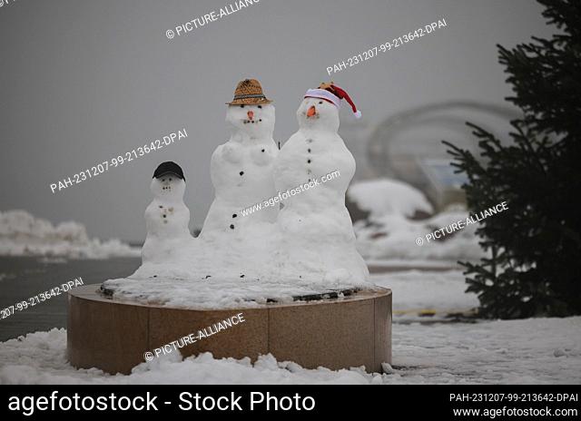07 December 2023, Schleswig-Holstein, Kellenhusen: A snow family stands on the snow-covered beach of the Baltic Sea in front of the Kellenhusen pier
