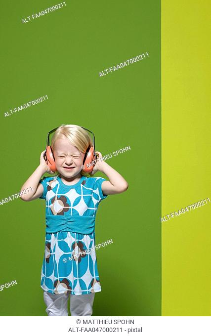 Little girl with eyes closed wearing protective headphones
