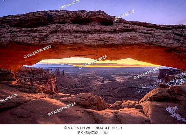 View through arch Mesa Arch at sunrise, Colorado River Canyon with the La Sal Mountains behind, view at Grand View Point Trail, Island in the Sky