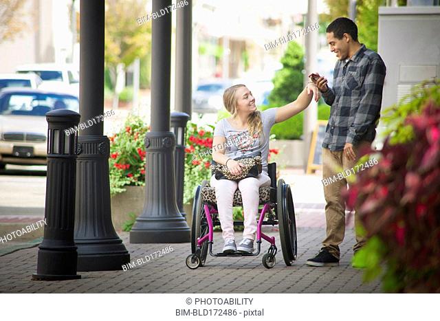 Couple using cell phone on city sidewalk