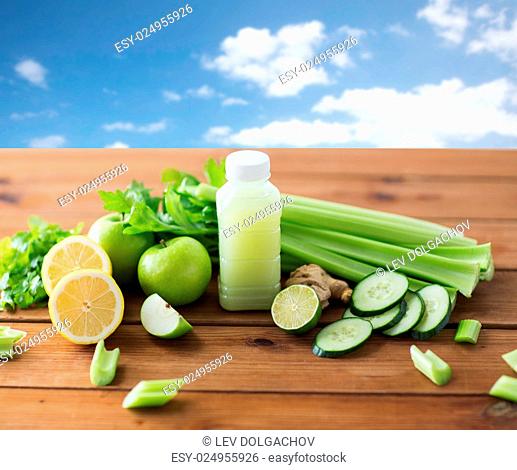 healthy eating, food, dieting and vegetarian concept - bottle with green juice, fruits and vegetables on wooden table over blue sky background