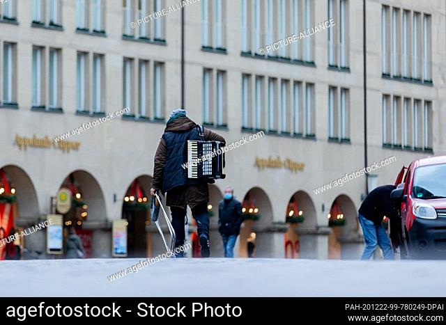 21 December 2020, North Rhine-Westphalia, Münster: A man with an accordion walks across Prinzipalmarkt. Photo: Rolf Vennenbernd/dpa
