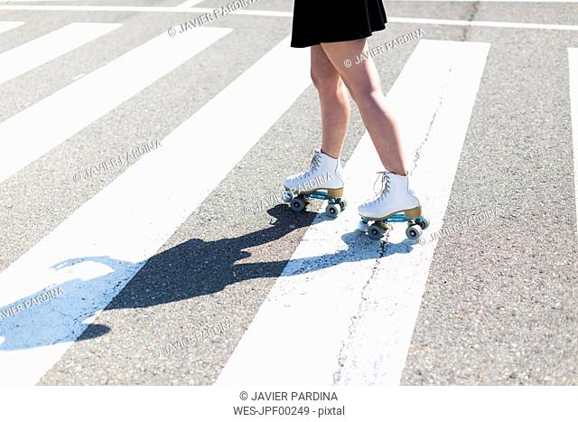 Young woman with roller skates on zebra crossing, partial view