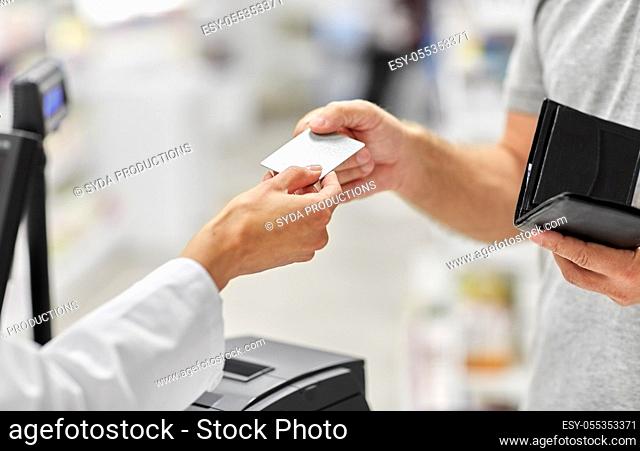 close up of hand giving bank card to pharmacist