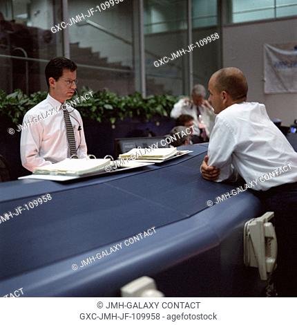 Michael F. Machula (left), at the booster console, converses with astronaut Frederick W. (Rick) Sturckow, spacecraft communicator (CAPCOM)