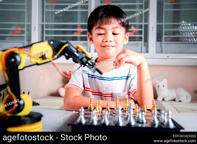 Asian little boy is playing chess with robot machine arm, STEM education E-learning, Funny children learning successful getting a lesson control robot arm
