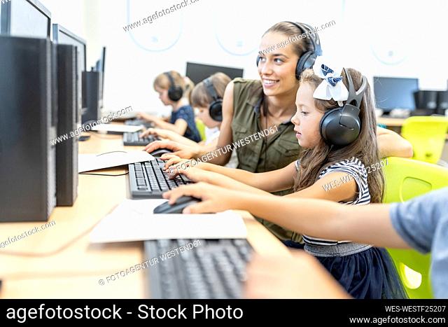 Teacher instructing student using computer in class at school