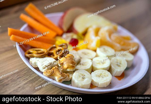 ILLUSTRATION - 08 November 2023, Saxony, Leipzig: ILLUSTRATION - A plate of snacks, fruit, vegetables and sweet nibbles sits on a kitchen table