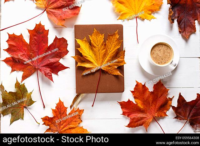 The concept of autumn mood. Morning coffee, diary and colored maple leaves