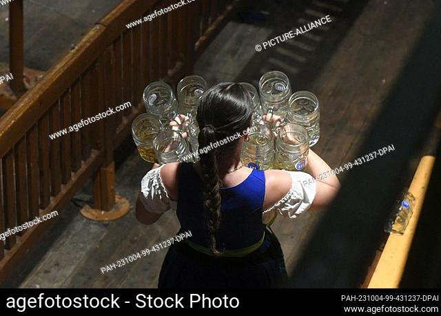 03 October 2023, Bavaria, Munich: A waitress carries empty steins after the traditional Kehraus in the Hofbräuzelt. The 188th Wiesn takes place this year until...