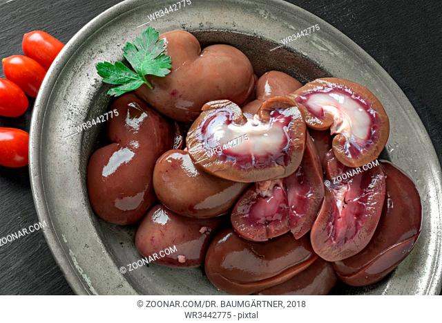 Lammnieren auf altem Zinnteller. Raw lamb kidneys in a pewter bowl