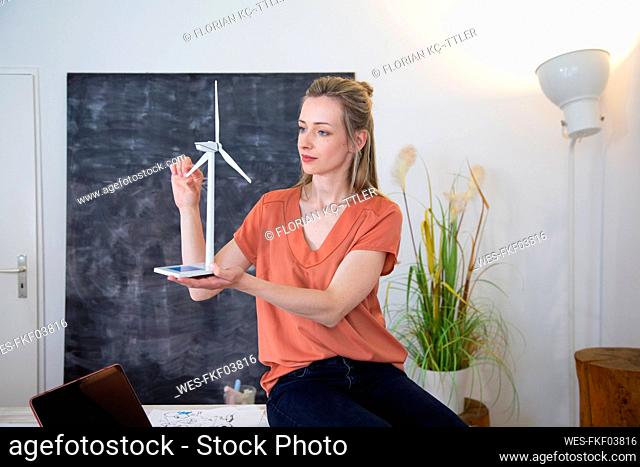 Woman in office holding wind turbine model
