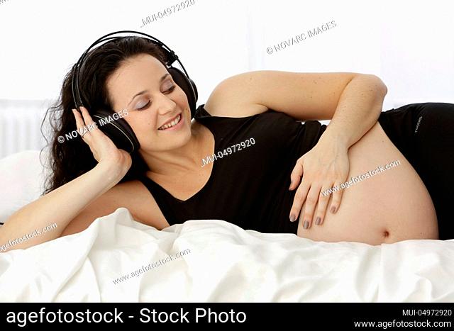 Pregnant woman listens to music with headphones