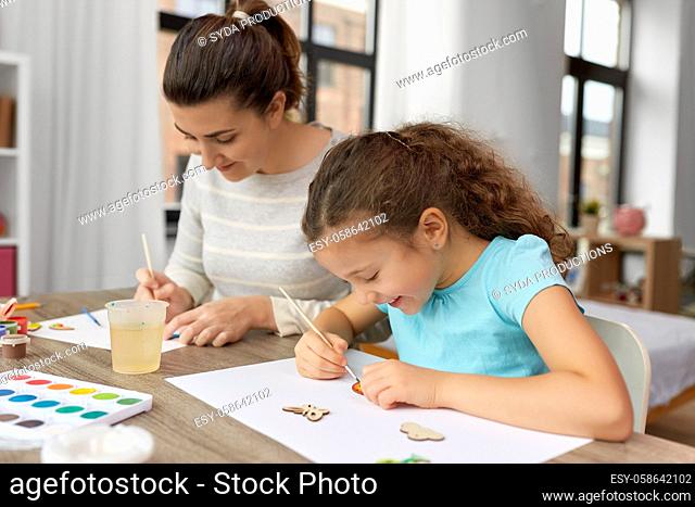 happy mother with little daughter drawing at home