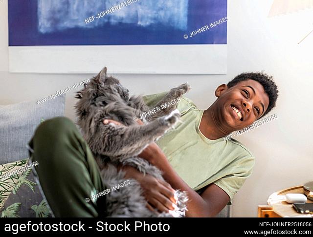 Teenage boy on sofa holding cat