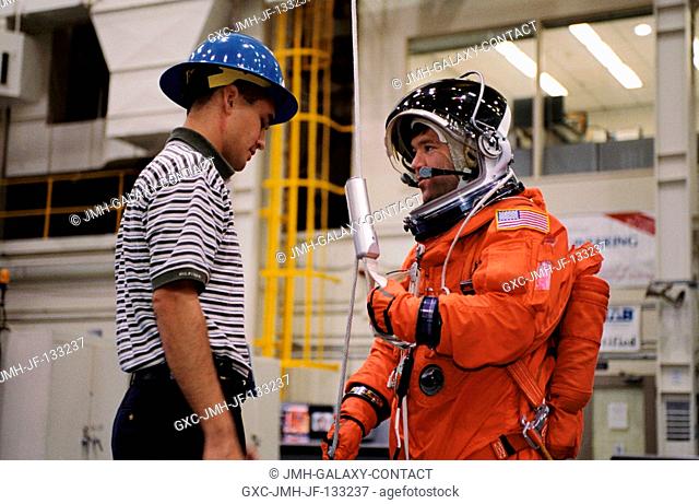 Astronaut Stephen N. Frick, STS-110 pilot, is briefed by United Space Alliance (USA) crew trainer Adam Flagan on the usage of the Sky-genie