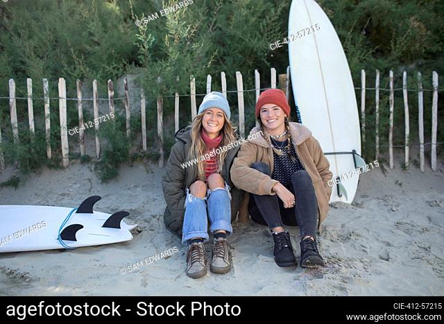 Portrait happy young female surfers with surfboards on beach path