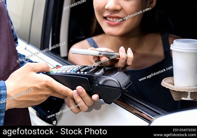 Asian woman customer make mobile payment contactless technology to waiter in drive thru food service while pickup coffee and bakery