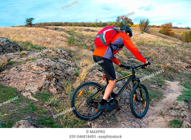 Cyclist in Red Riding the Bike on Autumn Rocky Trail. Extreme Sport and Enduro Biking Concept