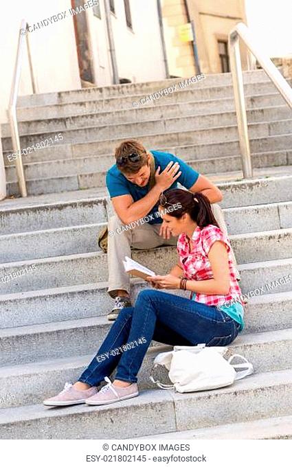 Young couple reading book guide on stairs